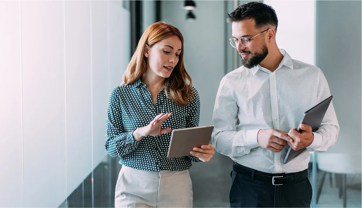 Two professionals discussing while walking in office.