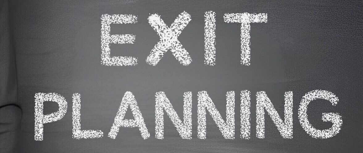 Close-up of chalk-written text 'EXIT PLANNING' on a blackboard.